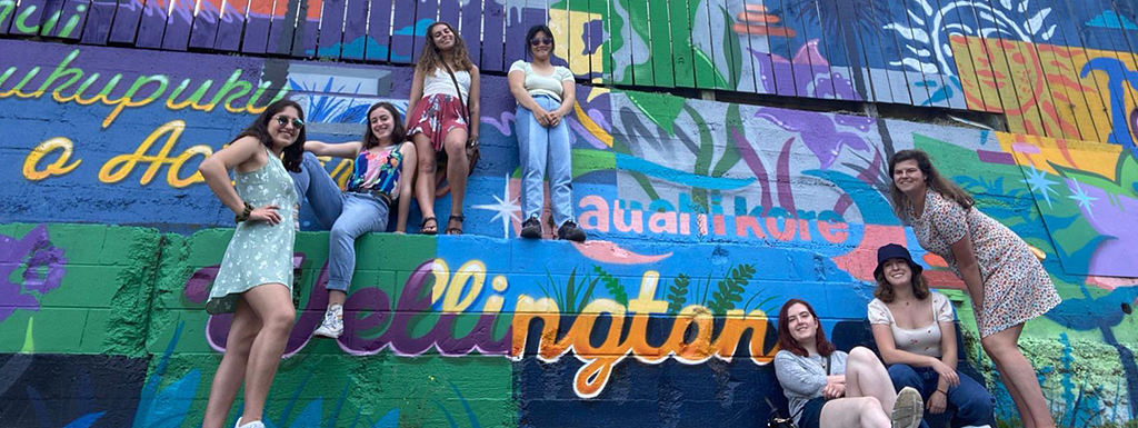 student pose for photo in front of painted wall 