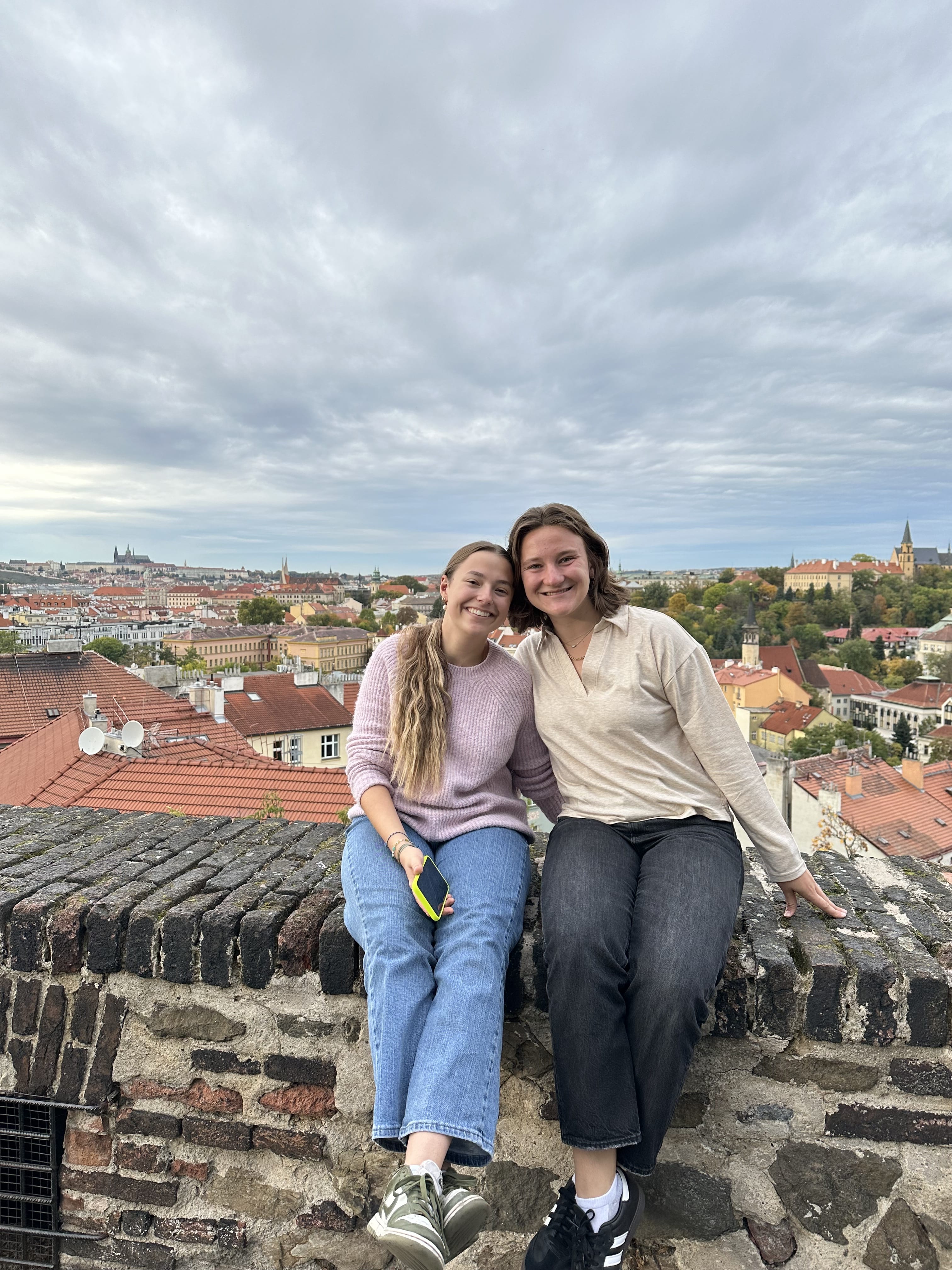 Madeline Lucy Pfeiffer and a friend sitting on a stone wall in France