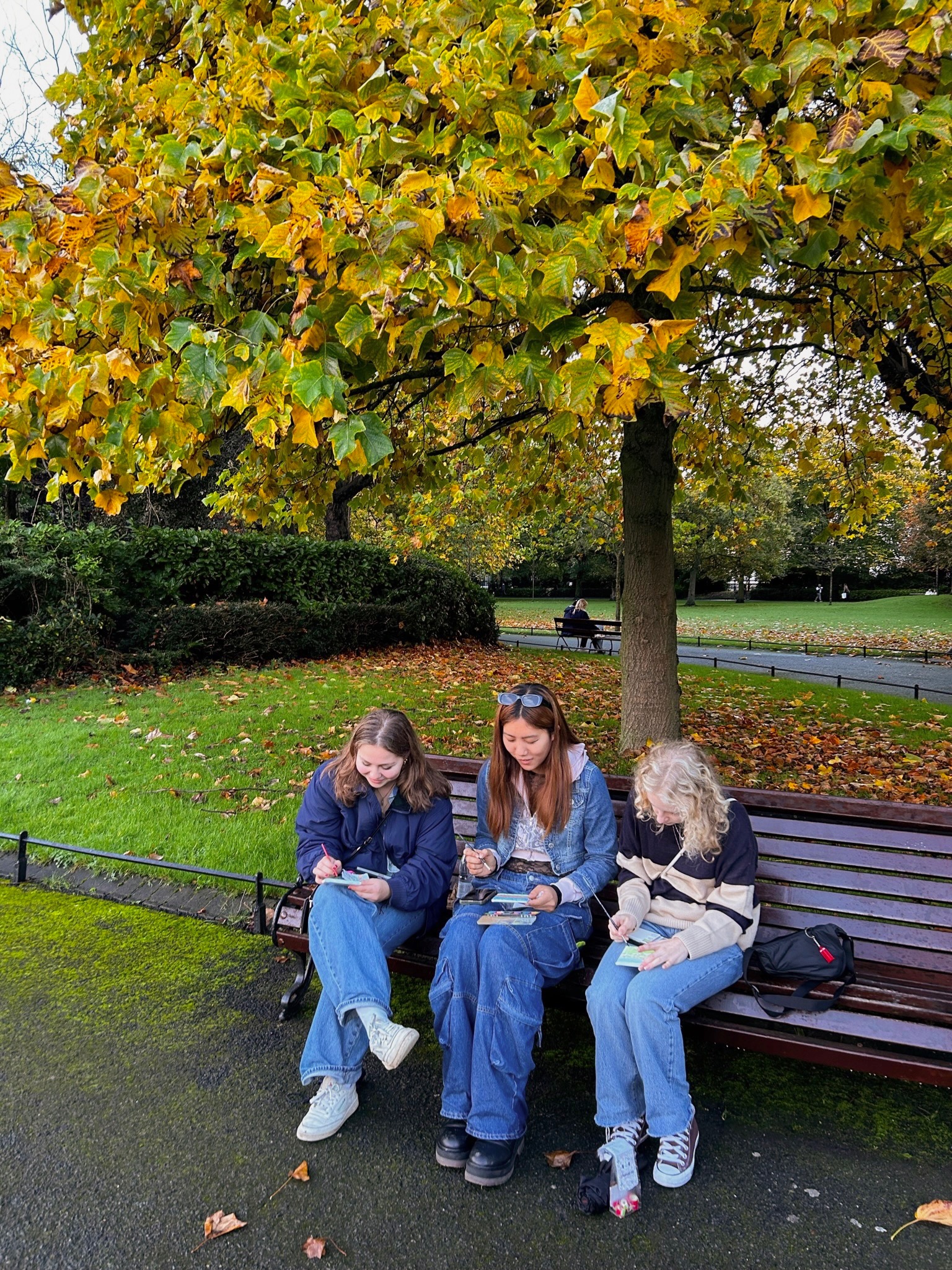 Lillian Buckley and two friends sitting on a park bench in London