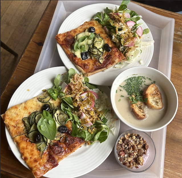 Various foods on a table including flat breads, greens, and yogurt