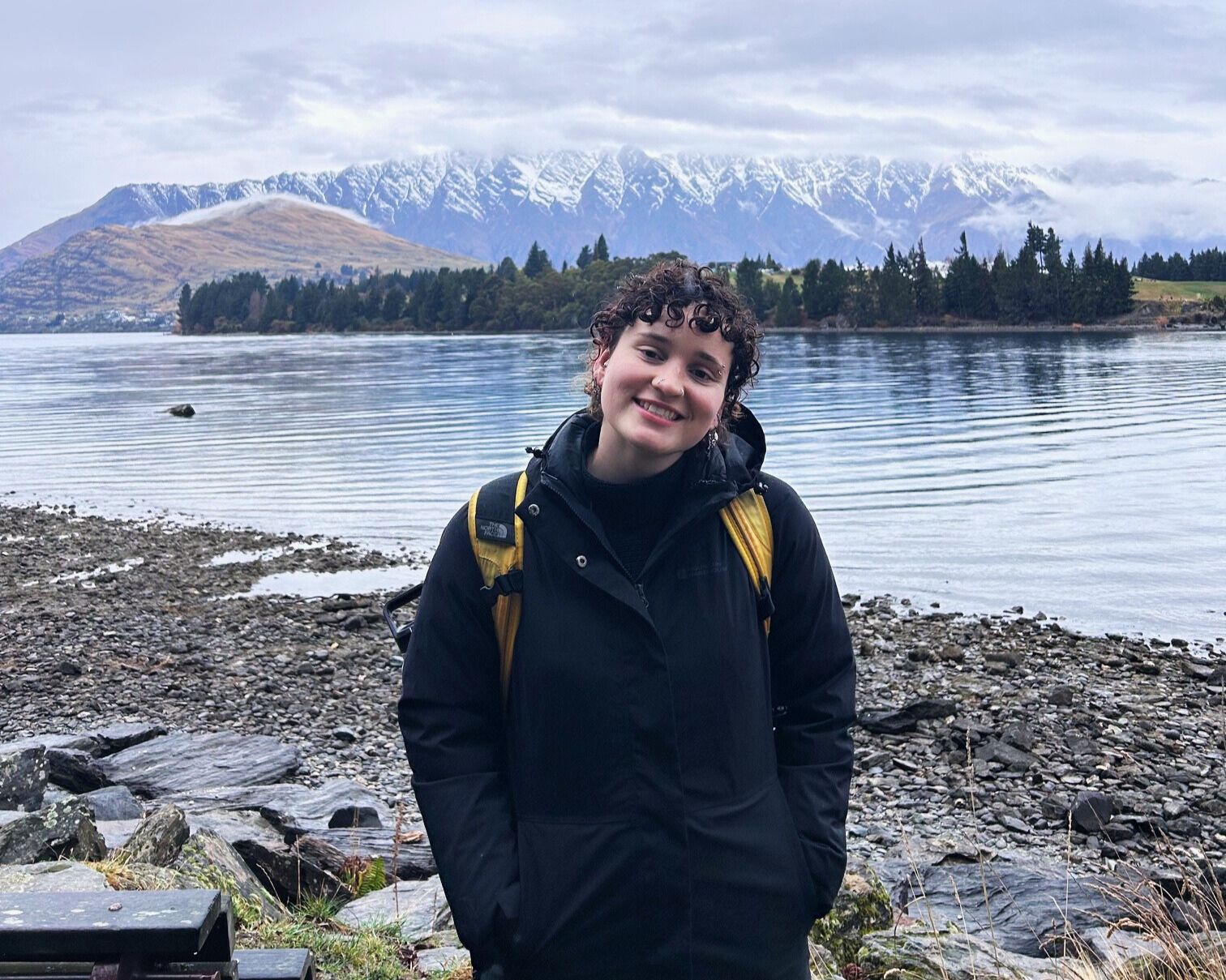 student posing in front of a lake with snow covered mountains in the background