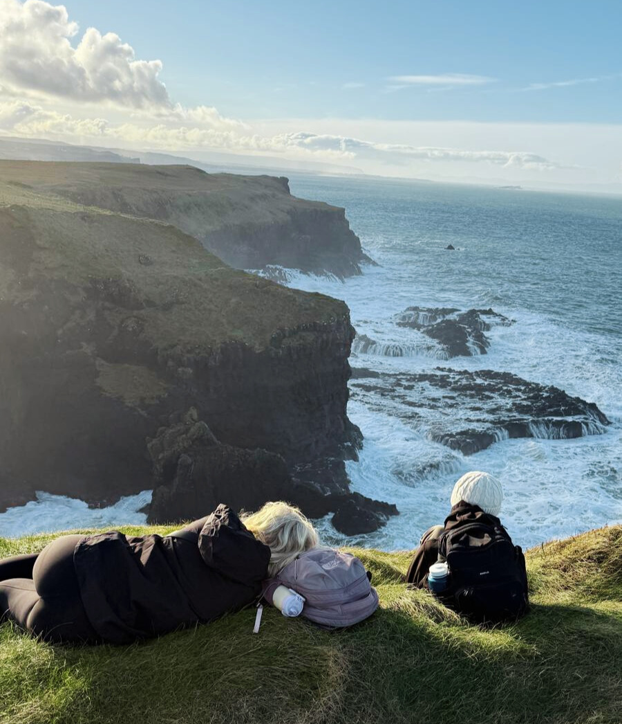 student overlooking at the seas while sitting on the seaside cliffs in Ireland