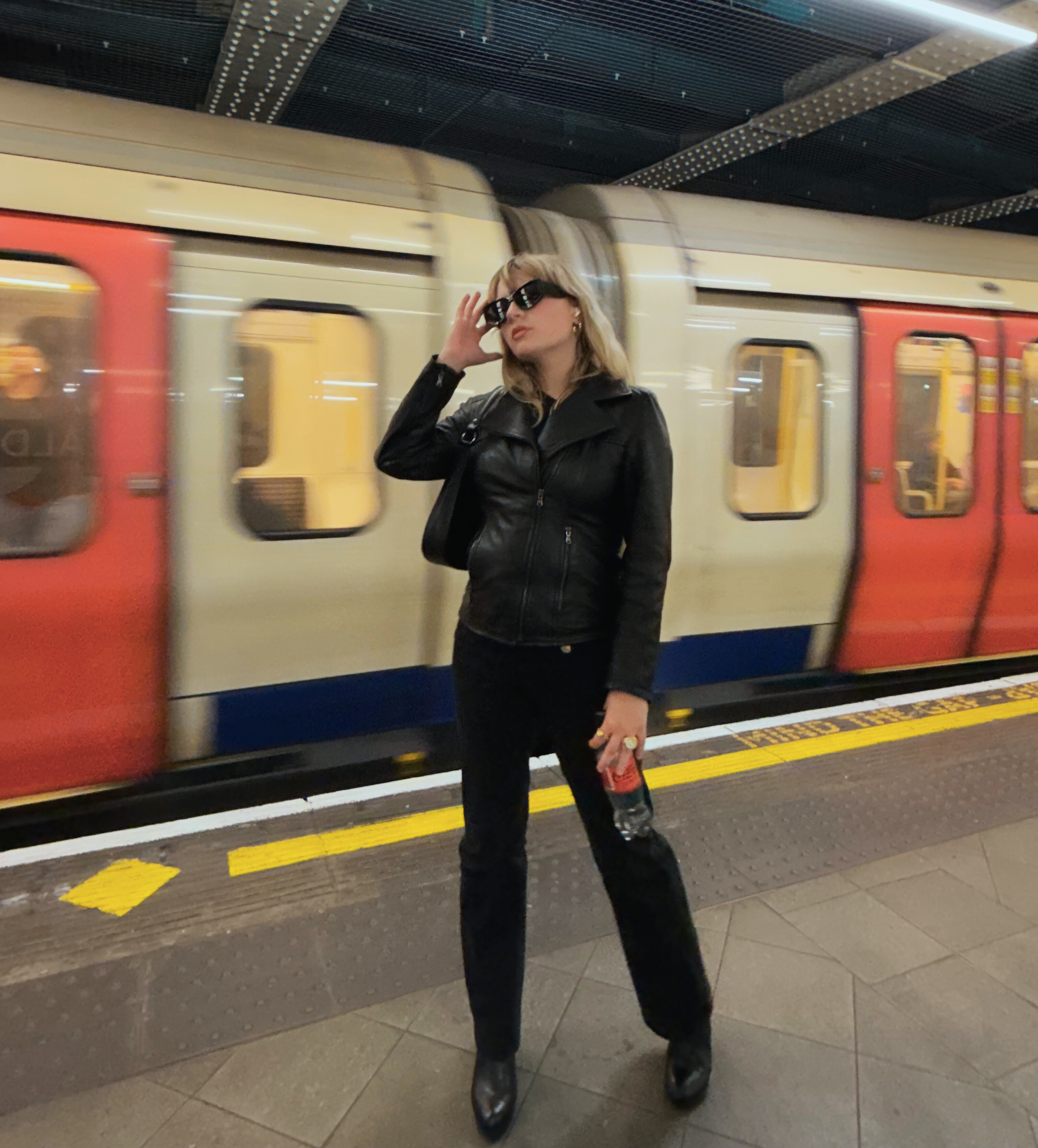 student posing in front of the passing subway