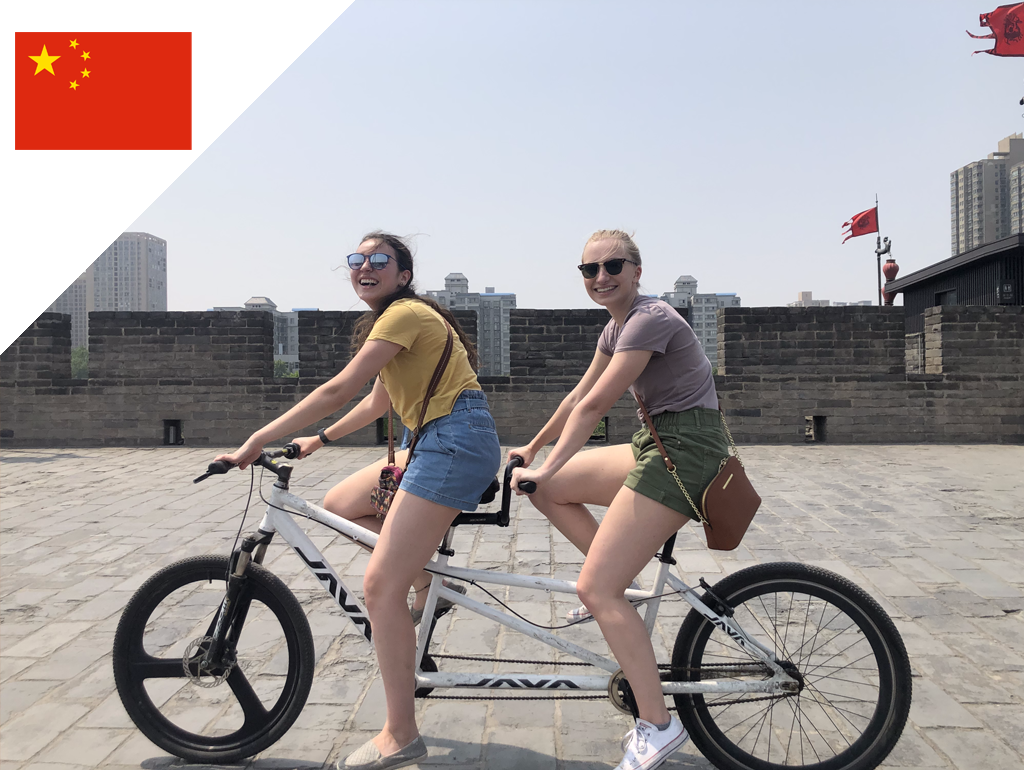Two GW students ride a tandem bicycle in China.