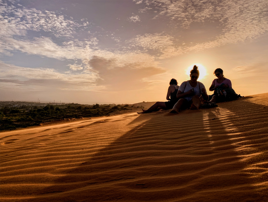 GW students sit atop a sand dune in Vietnam.