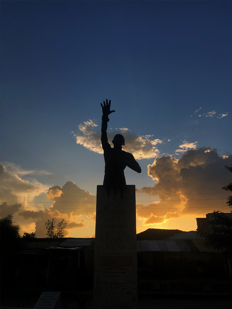 A statue of Benkos Bioho in San Bisilio de Palenque with a sunset in the background.