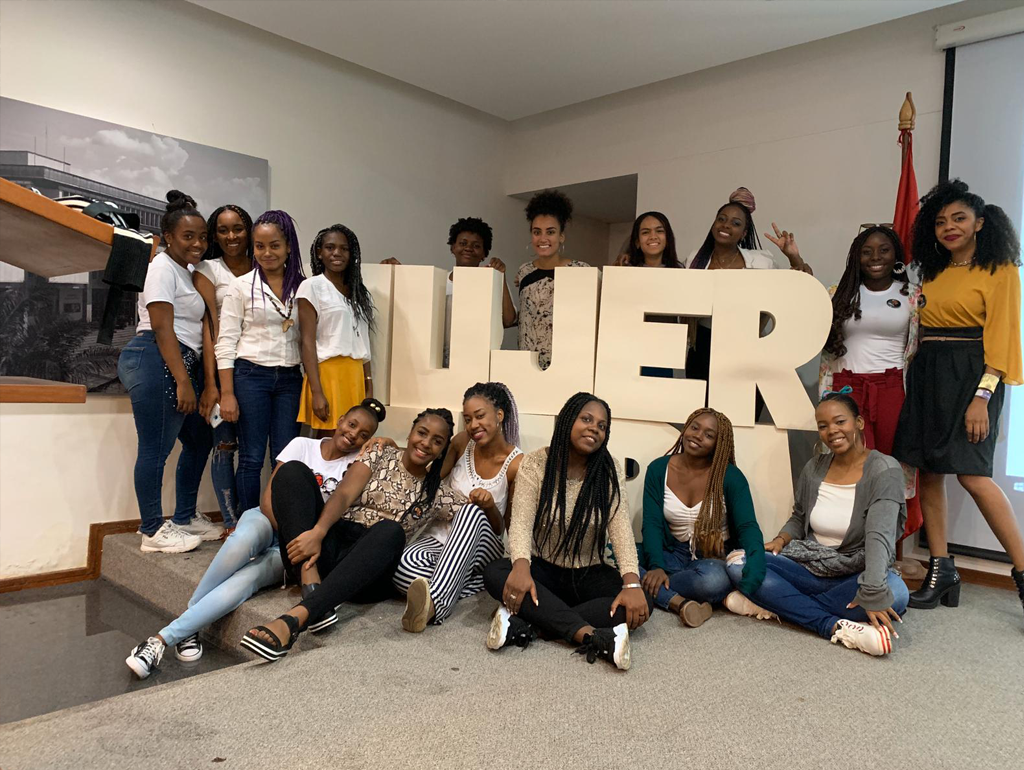 Many women pose around a large three-dimensional sign reading "Mujer Negra."