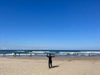 Morgan Limbaugh on the beach carrying a surfboard over her head.