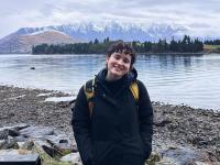 student posing in front of a lake with snow covered mountains in the background