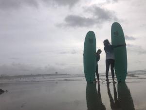 Two surfers stand on a beach