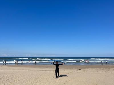 Morgan Limbaugh on the beach carrying a surfboard over her head.