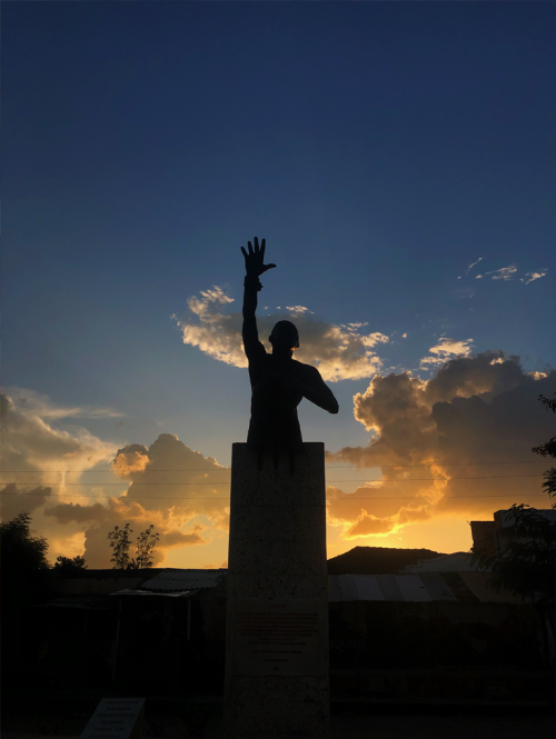 A statue of Benkos Bioho in San Bisilio de Palenque with a sunset in the background.