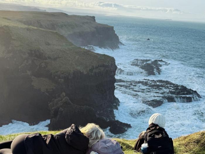 student overlooking at the seas while sitting on the seaside cliffs in Ireland