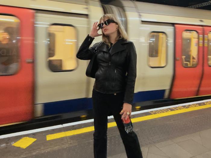 student posing in front of the passing subway