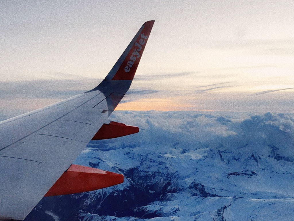 An EasyJet airplane wing is visible from high above a mountain range.